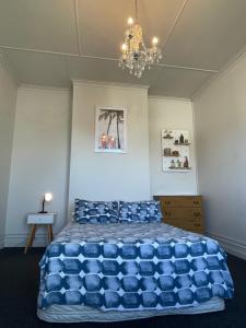 una camera da letto con un grande letto blu e un lampadario a braccio di Low Cost Accommodation a Dunedin