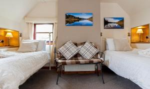 a bedroom with two beds and a chair in it at Kettle House B&B in Fort Augustus