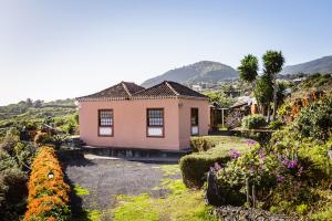 a small pink house in a garden with flowers at Carlota in Breña Baja