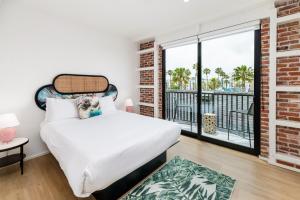 a bedroom with a white bed and a balcony at The Brick Boutique Hotel in Oceanside