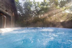 a hot tub with blue water in a backyard at Ellastone, woodland lodge with hot tub for 8 in Oakamoor