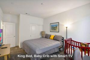 a bedroom with a bed and a baby crib with smart tv at Entire Private 4-BR, Mountain Edge, New House, Ranch, Gated Yard, Available Now in Menifee