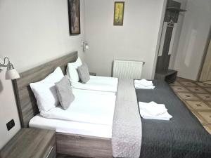 a bedroom with two beds with white sheets and pillows at Zajazd Fakir in Tapkowice