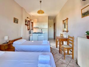 a room with two beds and a table and a kitchen at Marinos Studios and Apartments in Gialiskari