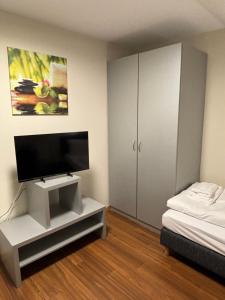 a bedroom with a flat screen tv and a bed at Pension Gergert am Neckar in Neckarsulm