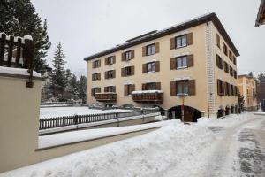 un edificio su una strada coperta di neve di fronte a un edificio di La Gemma a Celerina