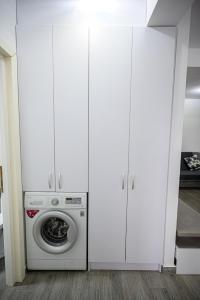 a laundry room with white cabinets and a washing machine at Apartament Azer Eforie Nord in Eforie +5 photos