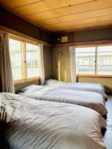 a row of beds in a room with windows at BEAR FOOT apartment in Yakumo +50 photos