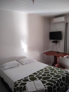 a bedroom with a bed with a desk and a television at Pousada Mato Grosso in Estivado