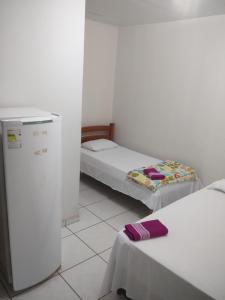 a room with two beds and a small refrigerator at Pousada Mato Grosso in Estivado
