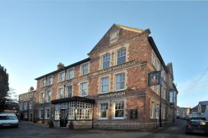 een oud bakstenen gebouw op de hoek van een straat bij The Duke of Wellington Wetherspoon in Minehead