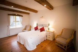 a bedroom with a white bed and two chairs at Rose Cottage in Doolin