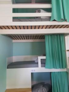 a bedroom with bunk beds with green curtains at Conde Surf Camp - Capsule Beds MIXED Dorm in Vila do Conde
