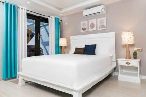 キングストンにあるCarter's Nest Villa - New Kingston - FIWIの青いカーテン付きのベッドルームの白いベッド1台 +51枚の写真