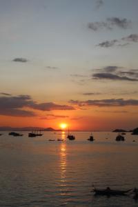 a sunset over the water with boats in the water at Komodo Shores Homestay in Labuan Bajo +27 photos