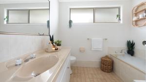 a white bathroom with a sink and a toilet at Thistledoo in Callala Beach