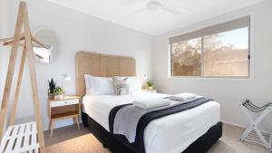 a white bedroom with a bed and a window at Thistledoo in Callala Beach
