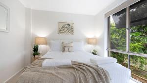 a white bedroom with a bed and a window at Thistledoo in Callala Beach +24 photos