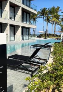 une piscine avec deux chaises longues à côté d'un bâtiment dans l'établissement Porto Alto Resort, à Porto de Galinhas