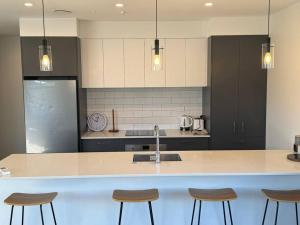 a kitchen with a sink and a counter with stools at Modern & Homely - Double Garage in Napier +7 photos