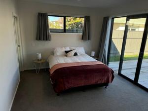 a bedroom with a bed and a large window at Modern & Homely - Double Garage in Napier