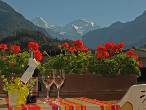 due bicchieri da vino seduti su un tavolo con fiori rossi di Post Hardermannli a Interlaken