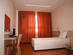 ソフィアにあるHotel Astraのベッドと机と窓のある寝室