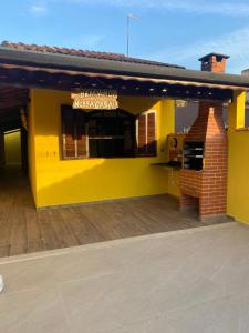 ein gelbes Gebäude mit einem Grill auf einer Terrasse in der Unterkunft Casa térrea em Caraguatatuba in Caraguatatuba