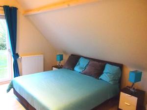 a bedroom with a bed with blue sheets and two lamps at Archipel Holiday Cottage in Ellezelles