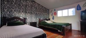 a bedroom with two beds and a wall covered in wallpaper at Villa Lore Glamping in Murillo