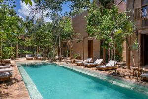 a swimming pool with chaise lounges and chairs near a house at 3BR Home in Gated Community with Private Rooftop Plunge Pool, Grill & Shared Pool in Tulum