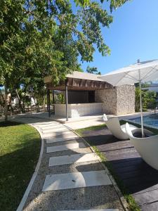 a walkway with a bench and an umbrella next to a pool at luxury central park lagunas in Tulum