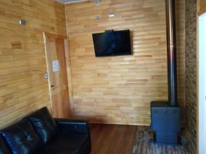 a living room with a black leather couch and a stove at Cabañas Mirador del Puma in Hornopiren