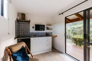 a room with a kitchen with a tv and a chair at River Haven in Tauranga