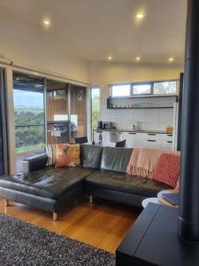 a living room with a black leather couch and a kitchen at Barossa Pavilions & Glasshouse in Lyndoch