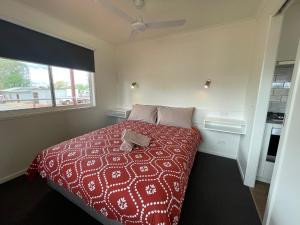 科巴Cobar Caravan Park的一间卧室配有一张带红色棉被的床和窗户。