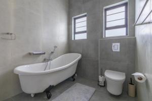 a bathroom with a white tub and a toilet at Nikita's Holiday Home - Walvis Bay in Walvis Bay