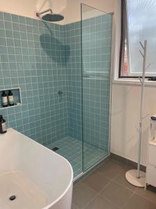un baño con bañera y ducha de cristal en Lorne Groovy Ocean View Log House, Pet Friendly, FREE WIFI wine & chocolates kangaroos in the evening, en Lorne