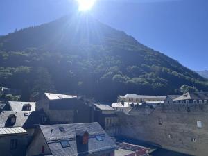 Une montagne où le soleil brille sur une ville dans l'établissement Chalet familial à Cauterets avec chambres spacieuses - FR-1-812-58, à Cauterets