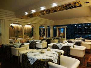 un restaurante con mesas blancas, sillas blancas y registrador en Hotel Roma, en Cesano Boscone