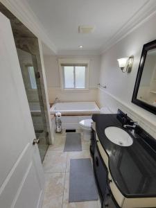 a bathroom with a tub and a sink and a toilet at Cozy Urban Cottage Close to Lake Ontario in Burlington