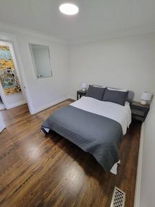 a bedroom with a bed and a wooden floor at Cozy Urban Cottage Close to Lake Ontario in Burlington