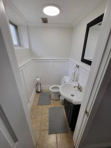 a white bathroom with a sink and a toilet at Cozy Urban Cottage Close to Lake Ontario in Burlington