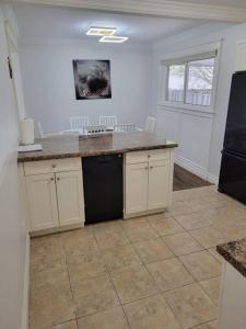 a kitchen with white cabinets and a black refrigerator at Cozy Urban Cottage Close to Lake Ontario in Burlington +22 photos
