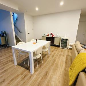 オークランドにあるRoom at Brand new house at Lincoln Roadの白いテーブルと椅子のあるリビングルーム