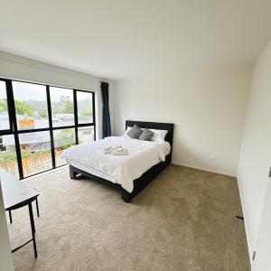 オークランドにあるRoom at Brand new house at Lincoln Roadのベッドと大きな窓のある寝室