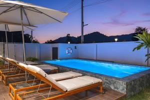 a swimming pool with lounge chairs and an umbrella at Pakbia Pool Villa Aonang Krabi in Ao Nang Beach