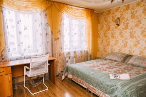 a bedroom with a bed and a desk and windows at Kakaduhome Guest Rooms in Khabarovsk