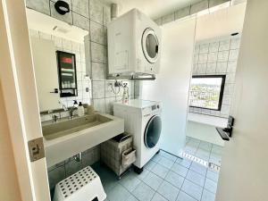 沖縄市にある家族限定の宿KyuuJitsuの洗面台と洗濯機を備えた白いバスルーム