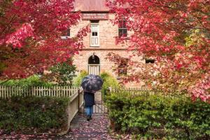 a person walking down a path with an umbrella in front of a building at The Quarters at Windsor House Walhalla in Walhalla